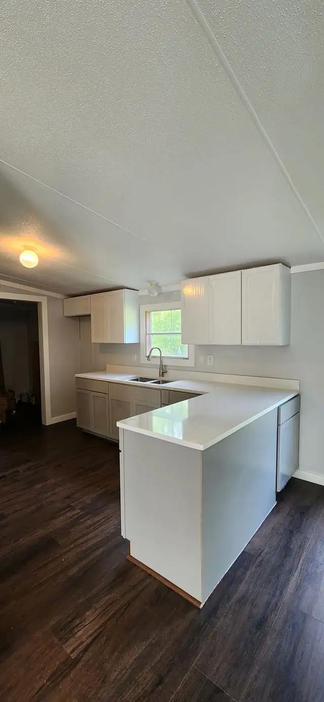 L-shaped kitchen with white quartz countertops, white wall cabinets and gray base cabinets