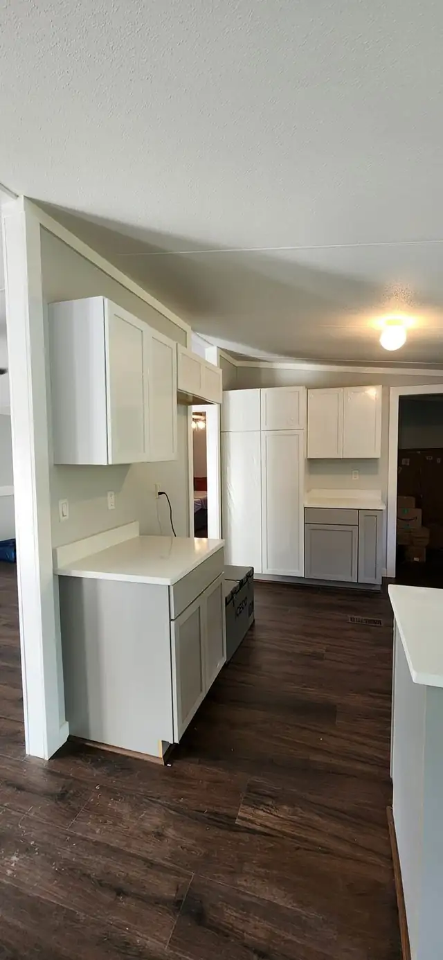 White shaker cabinets and a tall pantry with white countertops in an open kitchen